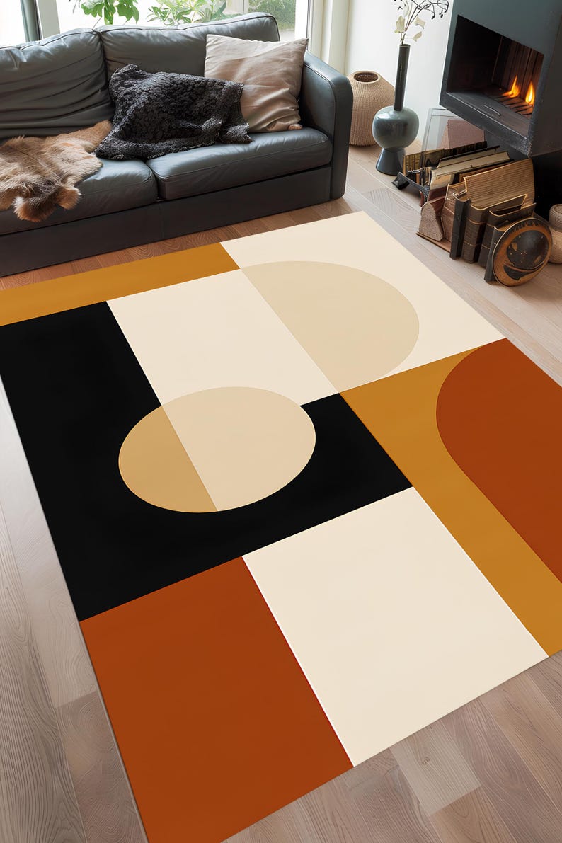 May include: A modern area rug with a geometric design. The rug features a combination of black, cream, tan, and rust-orange shapes, including squares, rectangles, and semi-circles. The rug is placed on a hardwood floor.