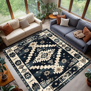May include: A large area rug with a geometric pattern in navy blue, cream, and tan. The rug features a central design with repeating shapes and a border with similar motifs. The rug is placed in a living room with two sofas and large windows.