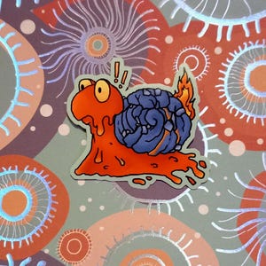 Puede incluir: Una pegatina con un caracol de dibujos animados con cuerpo naranja y caparazón azul. El caracol tiene ojos grandes amarillos y deja un rastro. El fondo es un diseño estampado con detalles en naranja y plata.