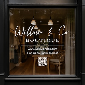 May include: A storefront window with a sign that reads "Willow & Co. BOUTIQUE" with the website address "www.willowandco.com" and the text "Find us on Social Media!" below. A QR code is displayed below the text. The storefront is lit with warm overhead lights and has a wooden floor.