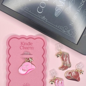 May include: Pink Kindle charm with a cowboy hat design on a pink card. Also, three cowboy boot and hat charms. The Kindle screen displays the text "A Book of Cowboy and Smut".