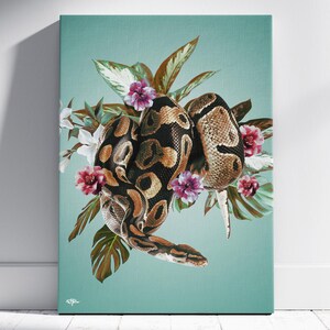Puede incluir: Impresión en lienzo que representa una serpiente enroscada con un patrón marrón y negro, rodeada de hojas tropicales y flores rosas y blancas. El fondo es de color turquesa sólido, creando un contraste llamativo.