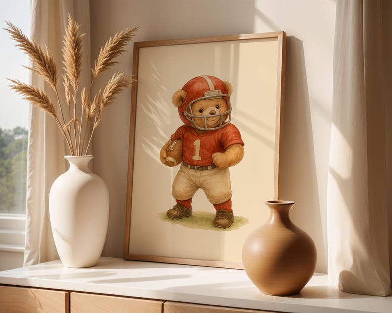 Pu&ograve; includere: Un'illustrazione incorniciata di un orsacchiotto che indossa una divisa da football rosso e bianca e un casco. L'orso tiene un pallone da football e sta in piedi su uno sfondo beige.