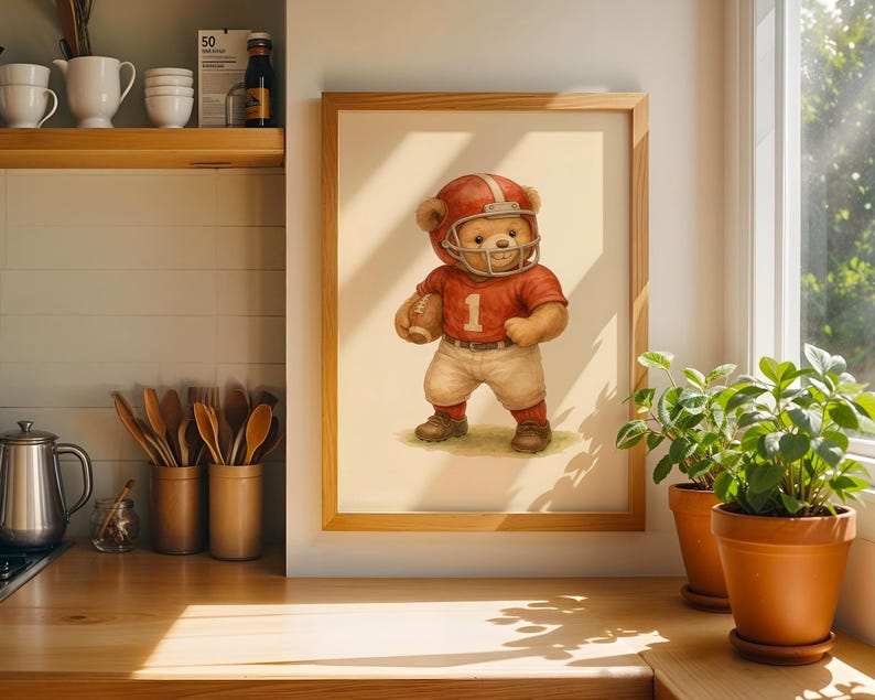 Pu&ograve; includere: Un'illustrazione incorniciata di un orsacchiotto che indossa una divisa da football rosso e bianca e un casco. L'orso tiene un pallone da football e sta in piedi su un campo verde. L'illustrazione &egrave; su uno sfondo bianco.