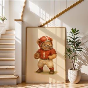 Pu&ograve; includere: Un orsacchiotto di peluche marrone che indossa una divisa da football rosso e bianca e un casco. L'orso tiene un pallone da football e sta in piedi su uno sfondo beige.