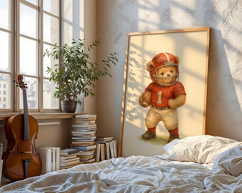 Pu&ograve; includere: Un'illustrazione incorniciata di un orsacchiotto che indossa una divisa da football rosso e bianca e un casco. L'orso tiene un pallone da football e sta in piedi su un campo verde.
