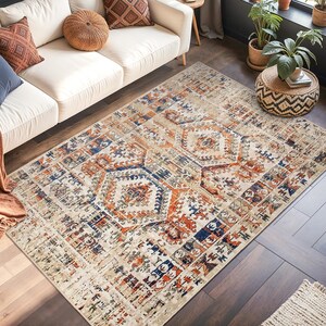 Può includere: Un soggiorno con un divano color crema, cuscini decorativi e un tappeto fantasia. Il tappeto presenta uno sfondo beige con disegni geometrici nei toni dell'arancione, blu e marrone. Piante e una finestra completano la scena. Il tappeto misura circa 200 x 300 cm.