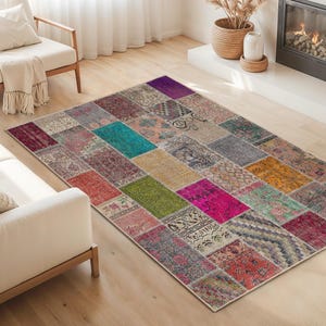Può includere: Un tappeto patchwork rettangolare con una varietà di colori e motivi. Il tappeto presenta quadrati di colore verde acqua, rosa, viola e beige. Il tappeto è posizionato su un pavimento in legno chiaro in un soggiorno.
