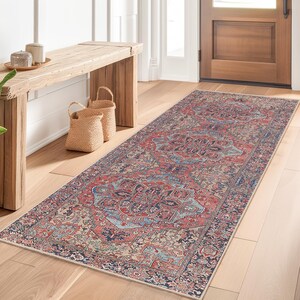 Könnte beinhalten: Ein rechteckiger Läufer mit traditionellem persischem Design in Rot-, Blau- und Cremetönen. Der Teppich liegt auf einem hellen Holzboden in einem Flur, mit einer Holzbank, Körben und einer Topfpflanze.