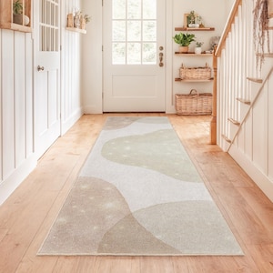 Könnte beinhalten: Ein langer, rechteckiger Teppich mit einem abstrakten Design in Beige-, Braun- und Hellgrüntönen. Der Teppich hat ein wellenförmiges Muster und liegt in einem Flur mit Holzböden und weißen Wänden. Der Teppich ist etwa 244 cm lang.