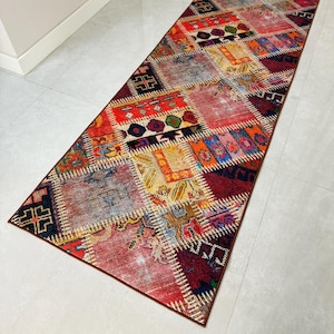 Puede incluir: Un corredor de patchwork colorido con un patrón de diamante. La alfombra está hecha de diferentes telas y colores, incluyendo rojo, azul, amarillo y verde. La alfombra tiene un borde marrón.