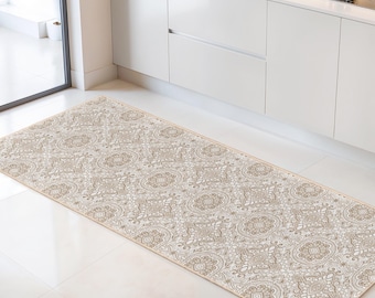 May include: A rectangular kitchen rug with a beige and white floral pattern. The rug is placed on a white tile floor in front of a white kitchen cabinet. The rug's design features a repeating pattern of stylized flowers and paisley elements.
