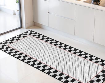 May include: A rectangular kitchen rug with a black and white checkered border and a white center dotted with small black circles. A thin red border frames the dotted center. The rug is placed on a white tile floor.