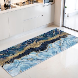 Peut inclure: Un long tapis de cuisine rectangulaire avec un motif de marbre. Le tapis présente des nuances de bleu, d'or et de marine, créant un aspect luxueux. Le motif a un effet marbré avec des veines dorées.