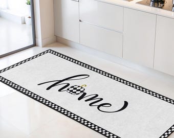 May include: A rectangular kitchen rug with a white background and a black and white checkered border. The word "home" is written in cursive in black, with a checkered design replacing the "o".