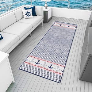 May include: A nautical-themed rug with blue and white stripes and a border featuring anchors and red accents. The rug is rectangular and placed on a boat deck, with a white sofa and pillows in the background. The rug's design evokes a coastal or marine theme.
