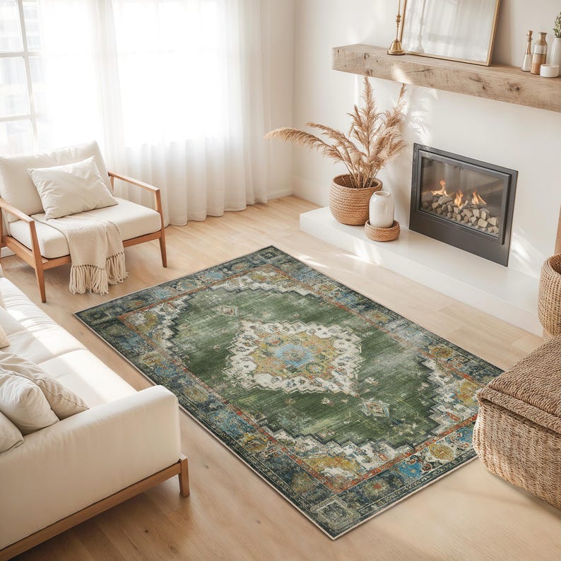 May include: A rectangular green area rug with a distressed, vintage-inspired design. The rug features a central medallion with cream, yellow, and blue accents, surrounded by a border of complementary colors. The rug is placed on a hardwood floor.