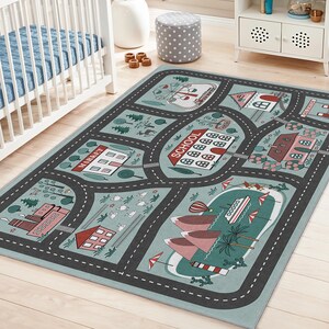 May include: A rectangular children's play rug with a road map design. The rug features roads, buildings, trees, and a beach scene. The color palette includes shades of blue, gray, red, and green. The word "SCHOOL" is visible on a red sign.