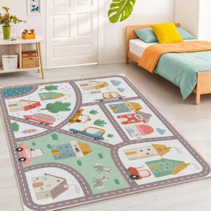 May include: A rectangular children's play rug featuring a city scene with roads, buildings, trees, and cars. The rug has a light background with gray roads, and colorful illustrations of houses, vehicles, and greenery. The rug is designed for imaginative play.