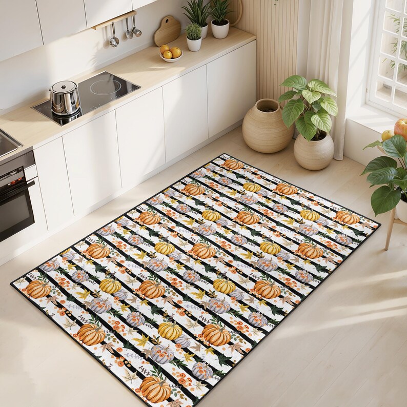 May include: A rectangular rug featuring a black and white striped design. The rug is adorned with watercolour pumpkins in orange, yellow, and grey, alongside autumn leaves. Suitable for a kitchen or dining area.