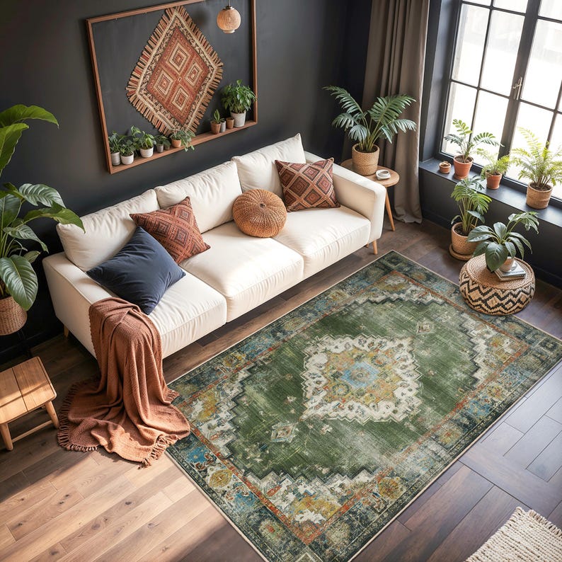 May include: An overhead shot of a living room with a white sofa, decorative pillows, and a green patterned rug. The room has dark walls, a large window, and several potted plants, creating a cozy and inviting atmosphere.
