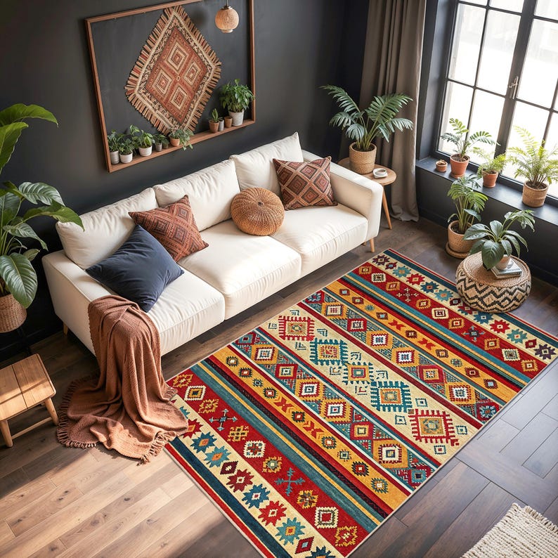 May include: A vibrant area rug with a geometric design in red, blue, yellow, and cream. The rug is rectangular and has a striped pattern with various shapes. It's placed on a wooden floor in a living room setting, adding warmth to the space.