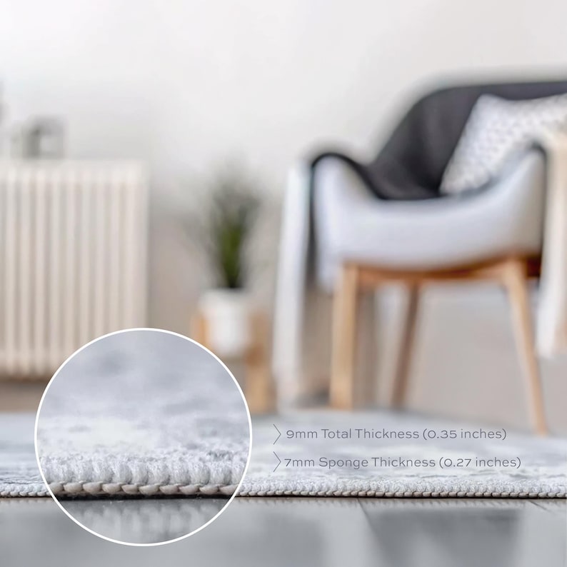 Peut inclure: Gros plan sur un tapis de couleur claire avec un bord d&eacute;taill&eacute;. L'&eacute;paisseur totale est de 9 mm, avec une &eacute;paisseur d'&eacute;ponge de 7 mm. Le tapis est sur un sol en bois fonc&eacute;, avec un arri&egrave;re-plan flou d'une chaise et d'une plante.