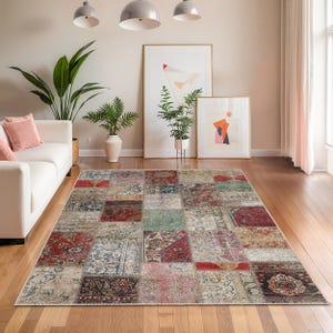 Peut inclure: Tapis rectangulaire en patchwork aux motifs vari&eacute;s, avec des couleurs rouge, bleu, vert et beige. Le tapis est pos&eacute; sur un parquet dans un salon, avec un canap&eacute; blanc et des &oelig;uvres d'art en arri&egrave;re-plan.