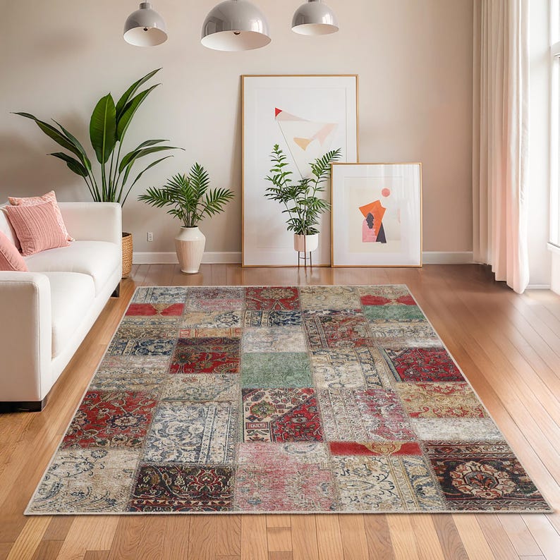 Peut inclure: Tapis rectangulaire en patchwork aux motifs vari&eacute;s, avec des couleurs rouge, bleu, vert et beige. Le tapis est pos&eacute; sur un parquet dans un salon, avec un canap&eacute; blanc et des &oelig;uvres d'art en arri&egrave;re-plan.