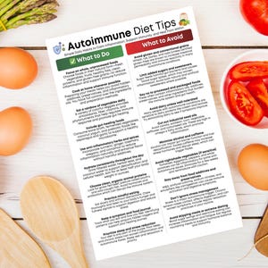 May include: An overhead shot of a white wooden table with various food items and a printed sheet titled "Autoimmune Diet Tips." The food includes tomatoes, eggs, asparagus, and carrots. Wooden utensils are also present.