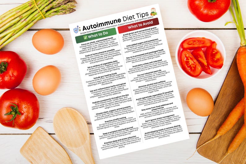May include: An overhead shot of a white wooden table with various food items and a printed sheet titled "Autoimmune Diet Tips." The food includes tomatoes, eggs, asparagus, and carrots. Wooden utensils are also present.