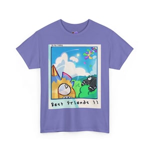 Puede incluir: Una camiseta de color lila con un gráfico de dibujos animados. El gráfico es una imagen estilo polaroid con el texto "Best Friends 11". La imagen muestra un personaje de dibujos animados con un fondo de cielo azul.