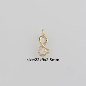 Peut inclure: Charm doré en forme de symbole infini avec un cœur en bas. La boucle infinie est ornée de petites pierres claires. Le charm mesure 22mm x 9mm x 2,5mm.