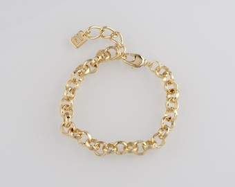 May include: Gold-toned chain bracelet with a lobster clasp closure. The bracelet features a series of interconnected, rounded links. A small, rectangular charm is attached near the clasp. The bracelet is displayed on a white background.