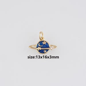 May include: A gold-colored planet charm with a blue enamel planet, adorned with stars and a crescent moon. A small clear gem is set on the ring. The charm measures approximately 0.5 x 0.6 x 0.1 inches. The text "size:13x16x3mm" is visible.