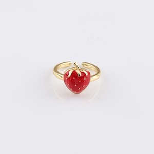 May include: A gold-toned adjustable ring with a red enamel strawberry design.