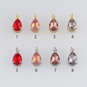 May include: Eight teardrop-shaped crystal pendants with gold and silver settings. The crystals are red, pink, and grey.
