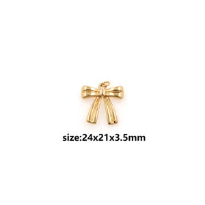Op de afbeelding: Gouden metalen strikbedel met een maat van 24x21x3,5 mm.