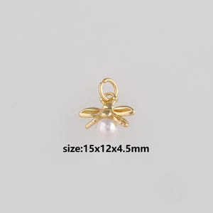 May include: A gold-coloured bee charm with a pearl centre. The charm has a loop at the top for attaching to jewellery. The text "size:15x12x4.5mm" is below the charm.