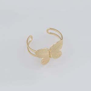 Pode incluir: Um bracelete de borboleta dourado. O bracelete é feito de metal e apresenta um design de borboleta detalhado.