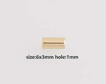 May include: A small, gold-colored cylindrical bead. The text below the bead reads "size: 6x3mm hole: 1mm". The bead is a simple, minimalist design, suitable for jewelry making or other crafts.