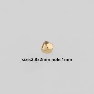 Puede incluir: Una cuenta dorada facetada de 2,8 mm x 2 mm con un agujero de 1 mm. La cuenta tiene una forma geométrica y un acabado brillante. El texto "size:2.8x2mm hole:1mm" está debajo.