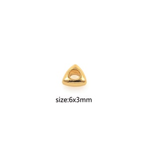 May include: Gold triangle bead with a hole in the center. The bead measures 6mm by 3mm.