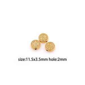 May include: Three gold-coloured round beads with detailed embossed designs. Each bead has a hole for stringing. The text on the image indicates the beads are 1.15cm in diameter, 3.5mm thick, and have a 2mm hole.