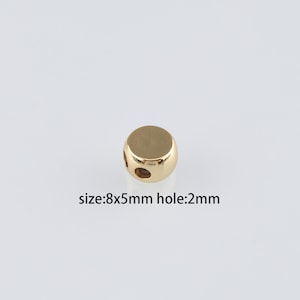 Może przedstawiać: Złota metalowa koralka z dwoma otworami. Koralka ma 8 mm na 5 mm i otwór o średnicy 2 mm.  size:8x5mm hole:2mm