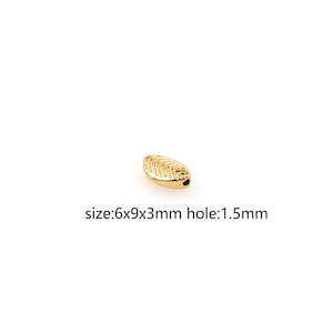 May include: Gold leaf-shaped bead with a 1.5 mm hole. The bead measures 6 mm x 9 mm x 3 mm.