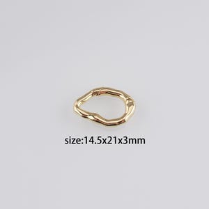 Könnte beinhalten: Goldfarbener Metallring mit unregelmäßiger, organischer Form. Der Ring misst 14,5 x 21 x 3 mm.