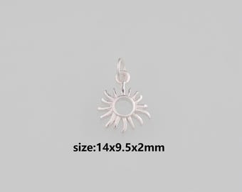 Puede incluir: Un dije de sol plateado con un anillo para sujetar a un collar o pulsera. El sol tiene un centro circular y rayos radiantes. El texto "size:14x9.5x2mm" está debajo del dije.