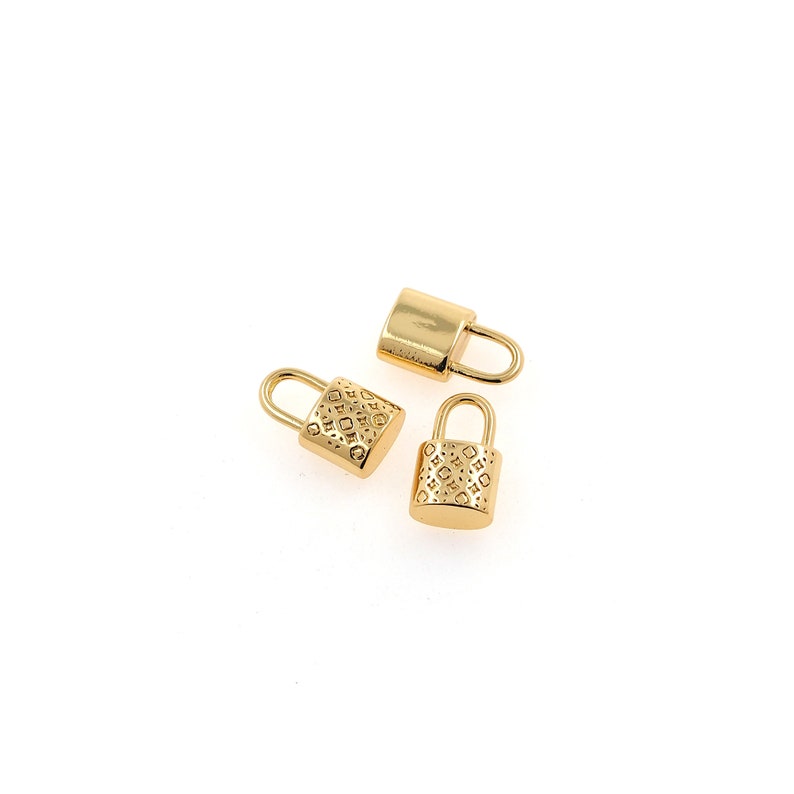 Puede incluir: Tres dijes de candado dorados con un dise&ntilde;o estampado. Los candados tienen un peque&ntilde;o lazo en la parte superior para sujetarlos a una cadena o pulsera.