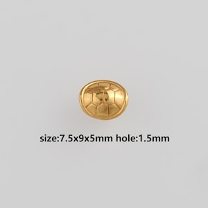 May include: A gold-colored, oval-shaped bead with a geometric pattern. The bead measures 7.5mm x 9mm x 5mm, with a 1.5mm hole. The bead is set against a light gray background.